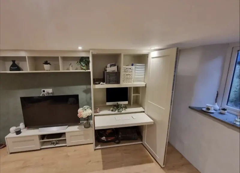 Built-in home office desk and shelving next to a TV unit and tall cupboard