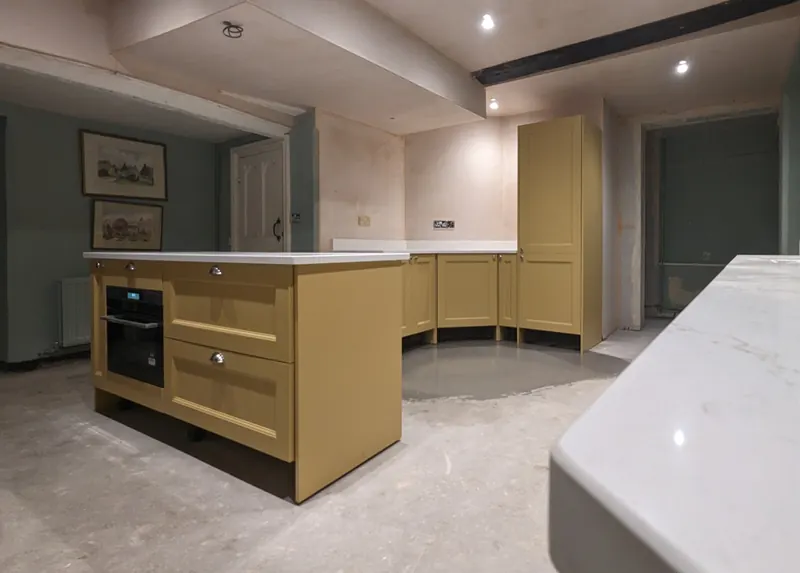 Painted shaker kitchen in mustard yellow with a matching island and tall larder units