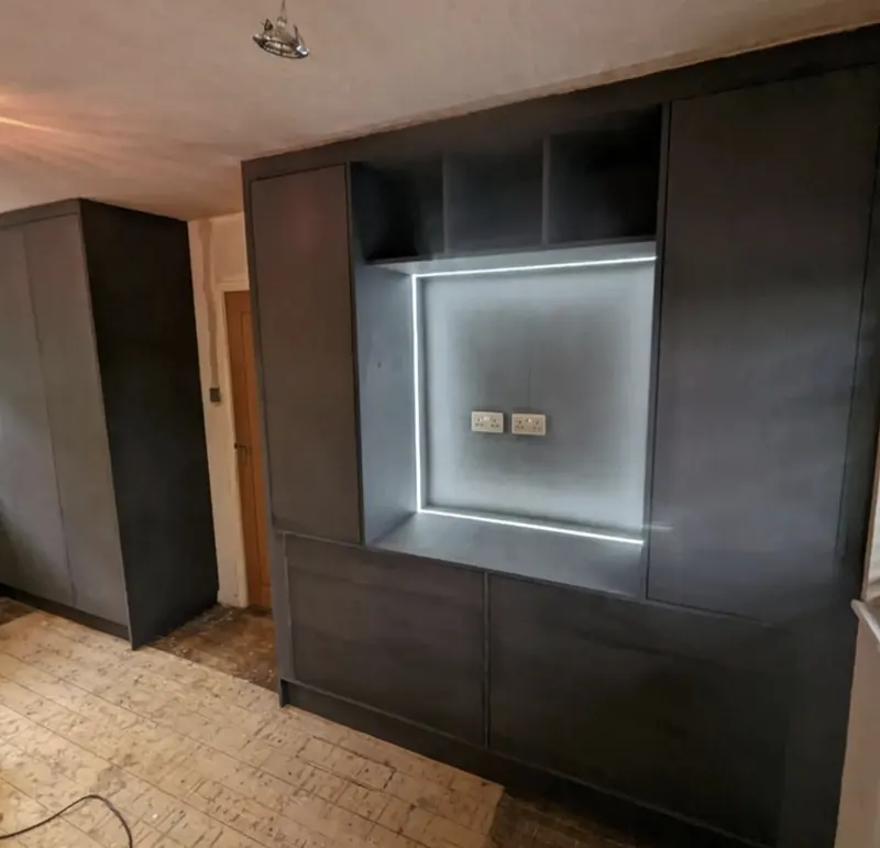 Dark built-in media unit with a backlit TV recess, display shelves and cupboards